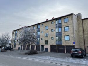 Ett gult trevåningshus med garageportar längst ner