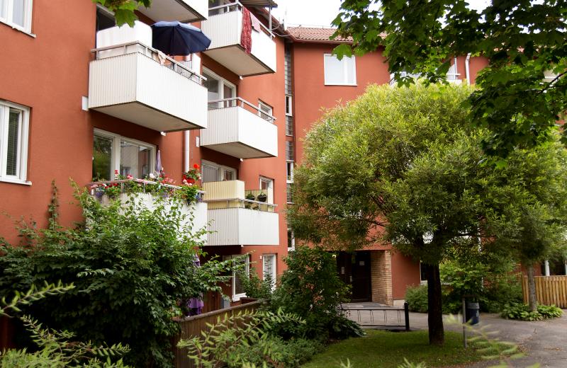 En lummig innergård med rött tegelhus och vita balkonger