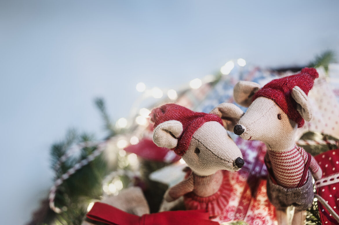 Två tygmöss med tomteluvor som sitter vid en ljusslinga
