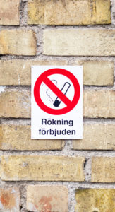 Foto. Rökförbudsskylt uppsatt på en tegelfasad.